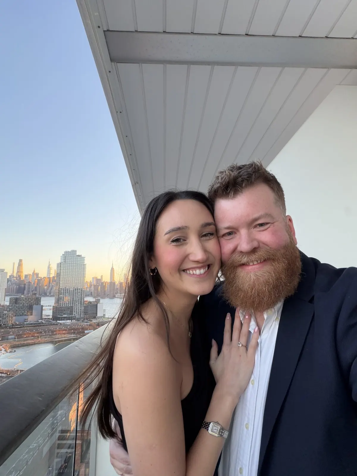Lucie and Simon moments after the proposal, the Manhattan skyline glowing behind them