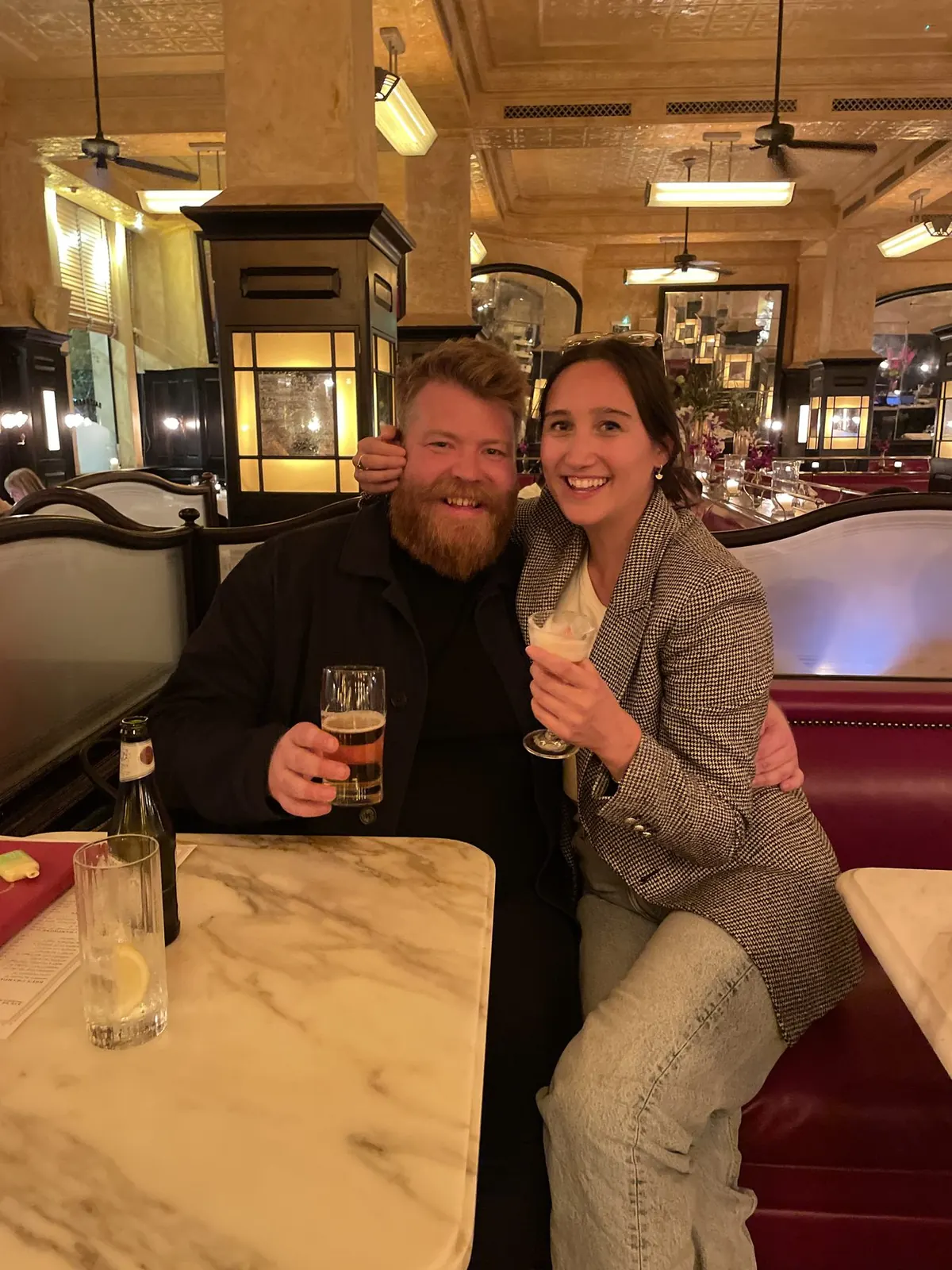 Lucie and Simon celebrating over drinks in a candlelit brasserie